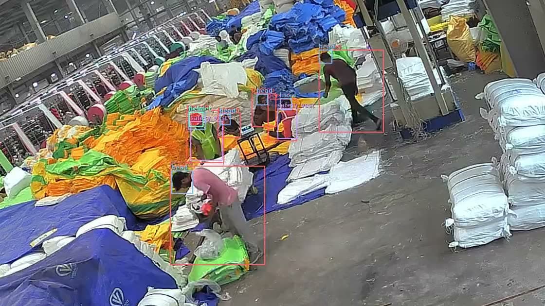 CCTV of a roll stock area with helmet and safety vest detections on the workers.